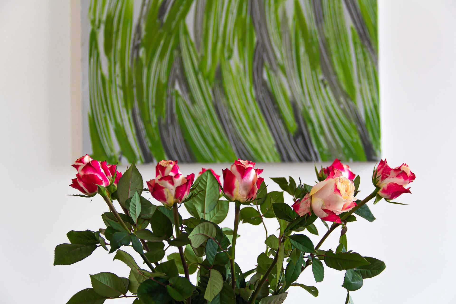 Fresh pink roses in front of an abstract painting in grey and green