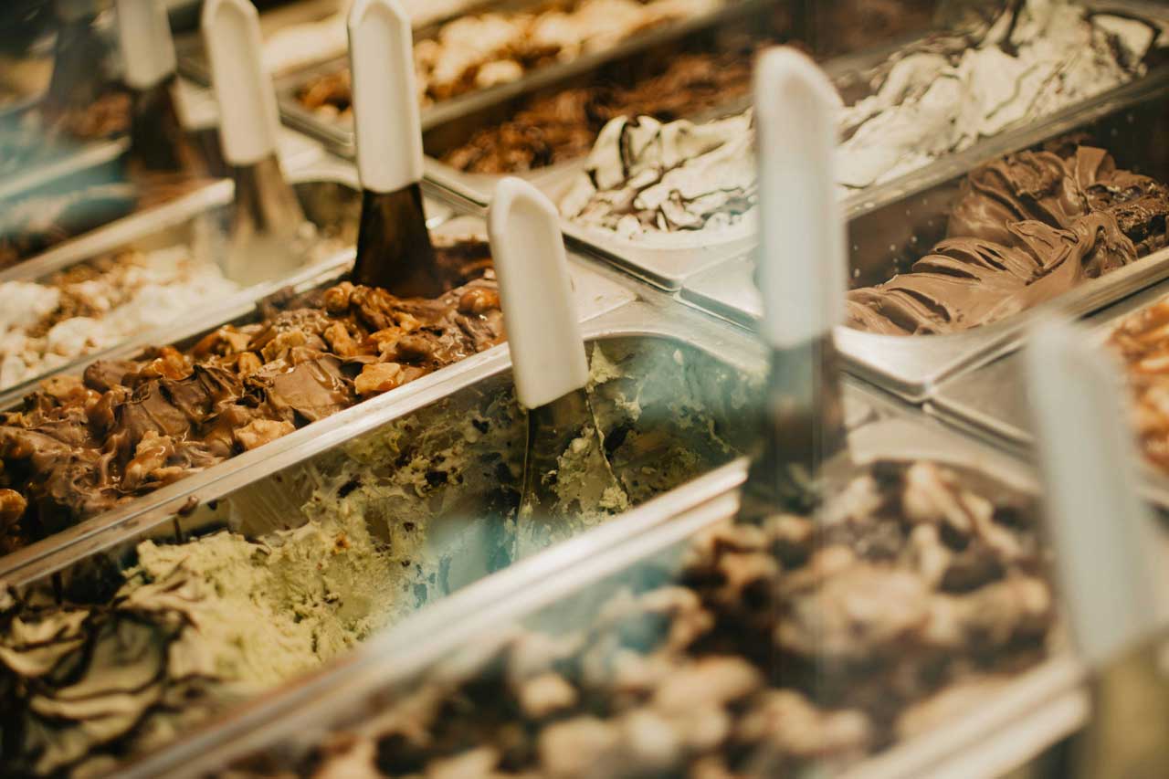 Assorted flavors of artisanal gelato in a display case at an ice cream shop