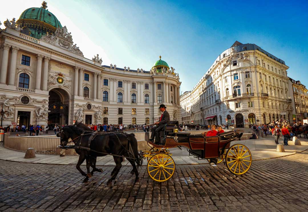 View of the Michaelerplatz in Vienna in the 1st district (inner city) with a coach in front and blue sky in the back