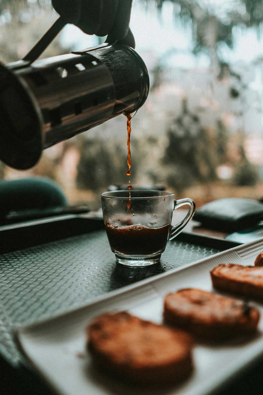 Fresh coffee poured from a fench press in to a glass mug in a cafe