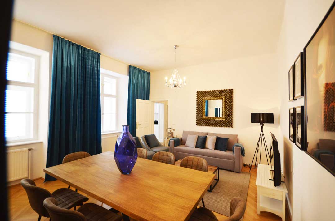 Grand living room; with cozy couch, big wooden dining table with fresh flowers on it