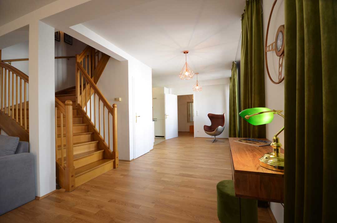 Big hallway with large stairs to the left and a beautiful green lamp shade on the right, in a business apartment in Vienna
