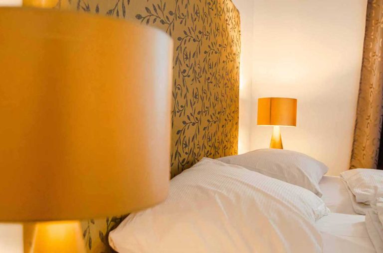 Golden lampshades besides a cozy kingsize bed