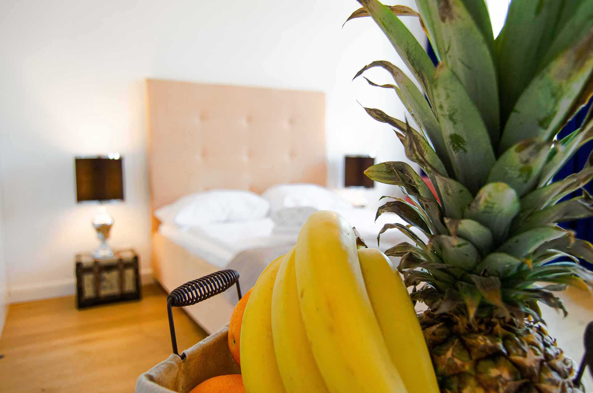 Bowl with fresh fruit; in the back a beige velvet kingsize bed