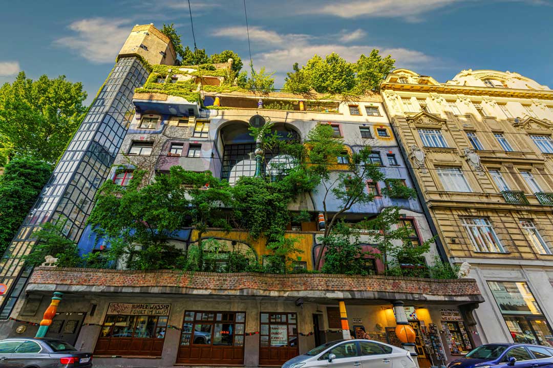 Famous Hundertwasserhaus in Viennas 3rd district, green trees und sunny view