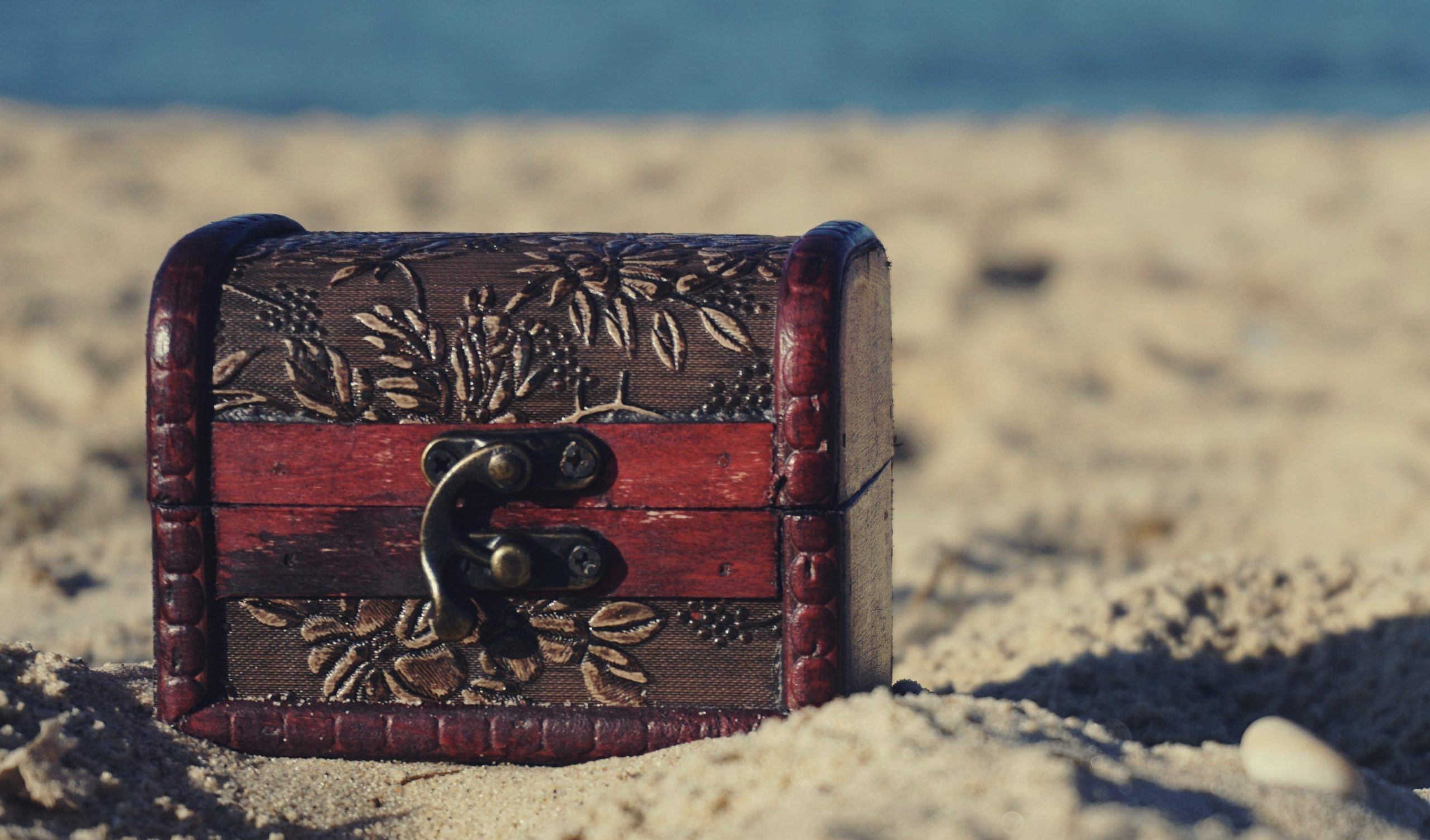A treasure chest on the beach as a motive for the hidden gem text.