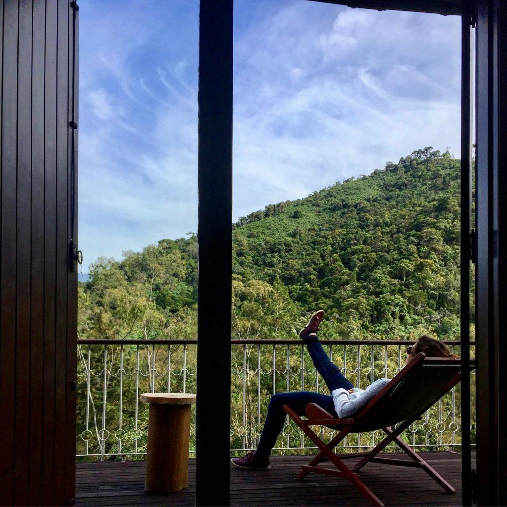 A person chilling on the balcony in a lounge chairoverlooking nature