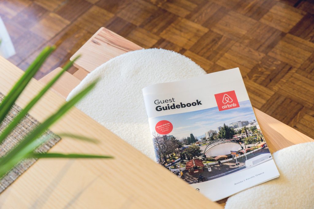 An Airbnb guest guide book cover on a bench in the living room.